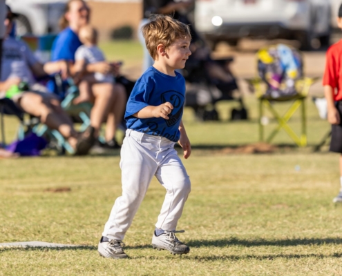 Young Paladin athlete running across a grass field during a recreational sports game.