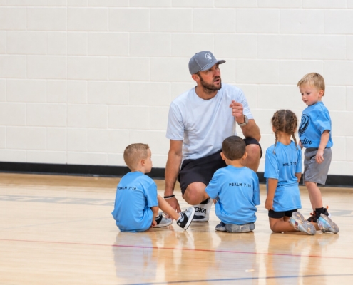 Youth basketball coach speaking with 4 young athletes.